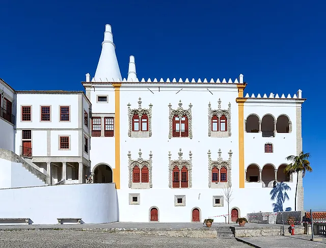 The white façade of the National Palace of Sintra with its two conical kitchen chimneys and Manueline windows