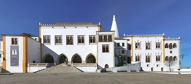 The long white front of the National Palace of Sintra beneath its twin conical chimneys