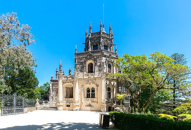 The neo-Manueline Regaleira Palace framed by trees under a blue sky